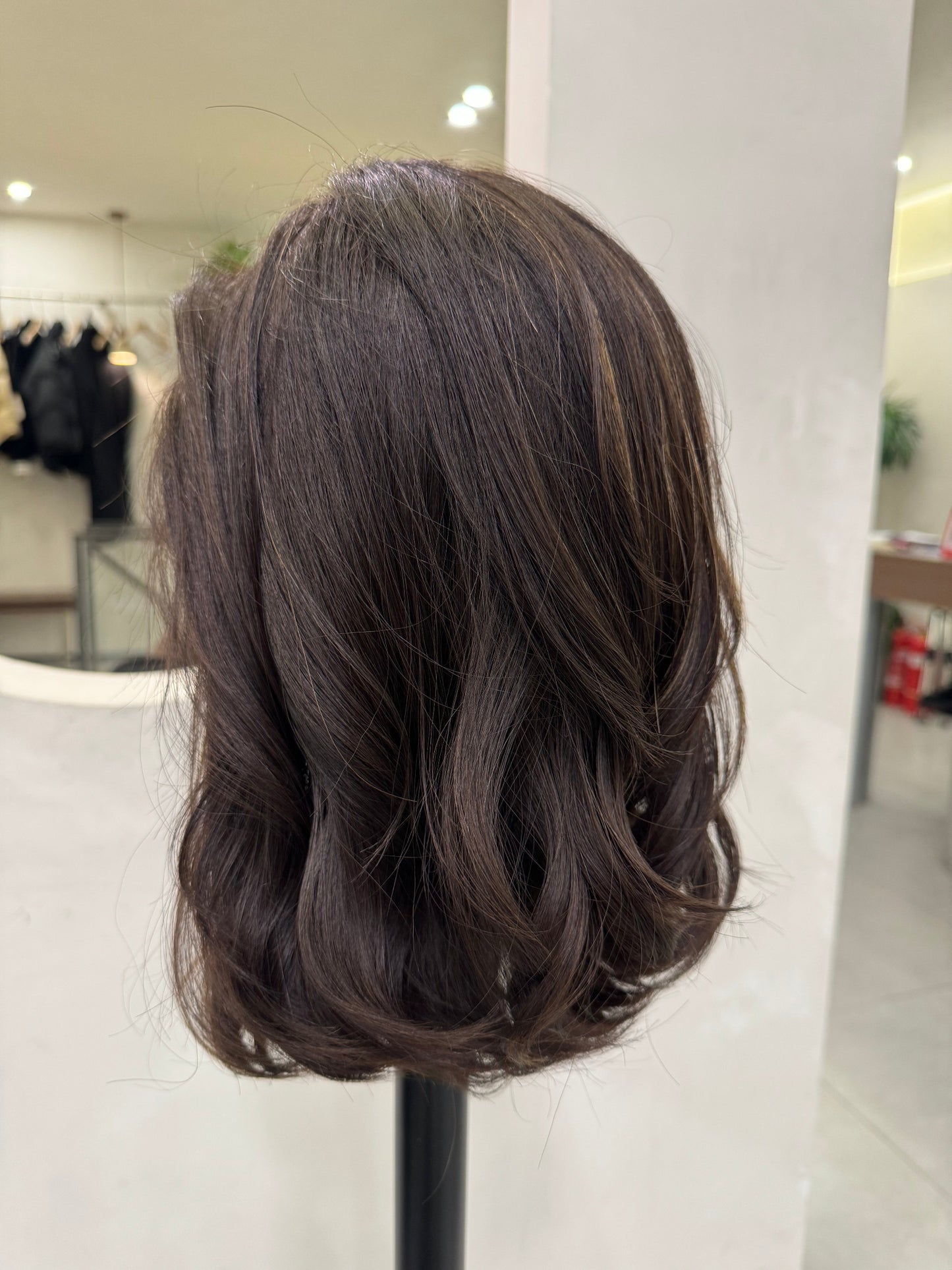 Dark brown hairpiece on a white surface with a blurred background